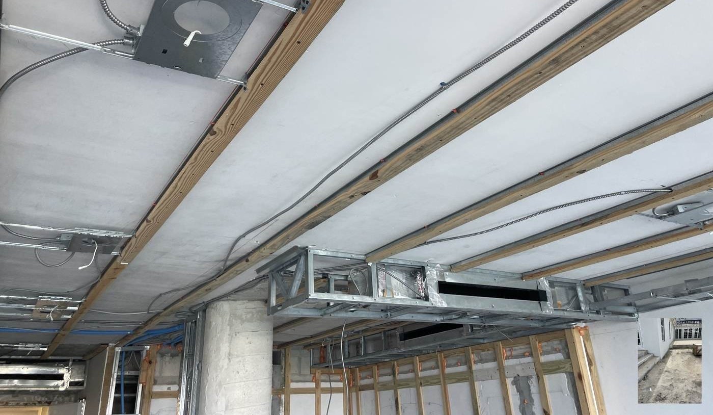 Overhead view of ceiling framing with recessed light housings, conduit and ductwork.