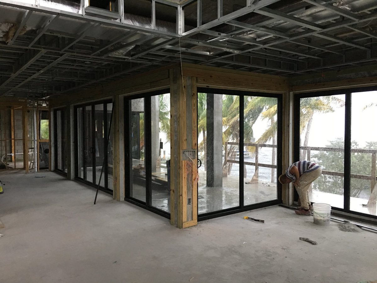 Interior of a building under construction showing installed sliding glass doors and a worker.