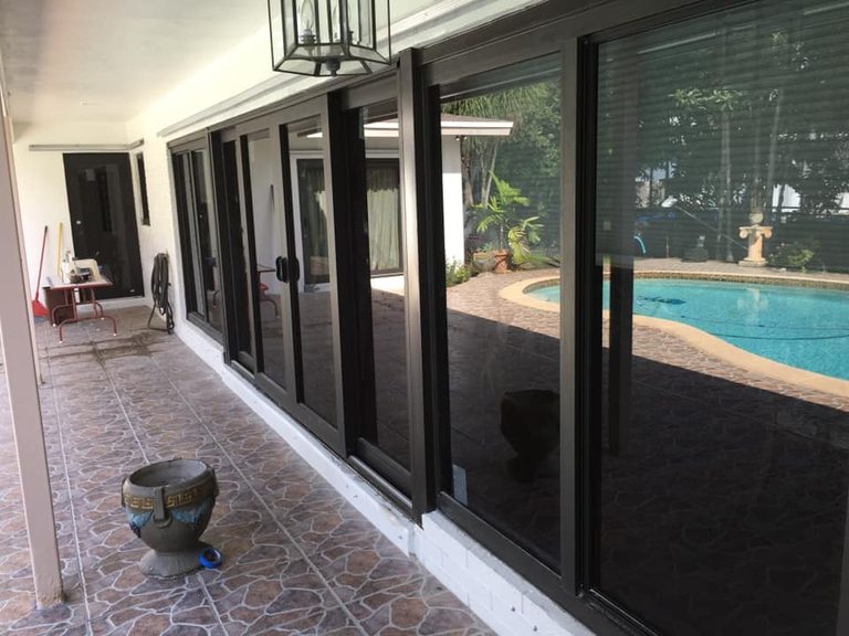 Dark-framed sliding glass doors installed on a patio next to an outdoor pool.